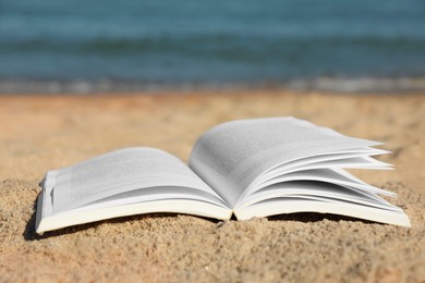Photo of Open book on sandy beach near sea