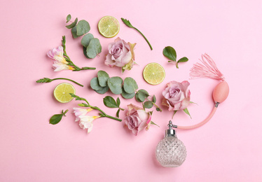 Photo of Beautiful flat lay composition with bottle of perfume, lime, eucalyptus and flowers on pink background