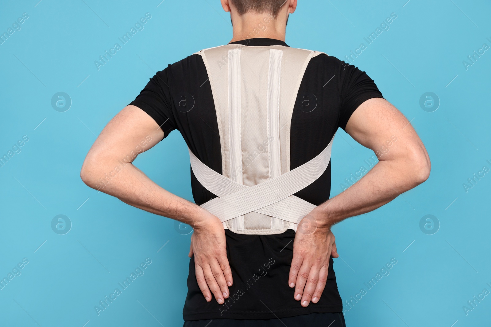 Photo of Closeup of man with orthopedic corset on blue background, back view