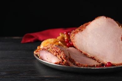 Plate with delicious ham on grey wooden table against black background