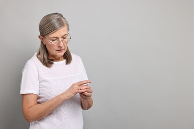 Photo of Arthritis symptoms. Woman suffering from pain in fingers on gray background, space for text