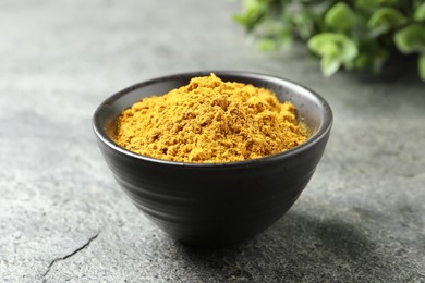 Photo of Dry curry powder in bowl on dark textured table, closeup