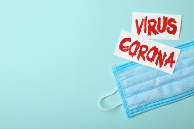 Photo of Phrase CORONA VIRUS and medical mask on light blue background, flat lay. Space for text