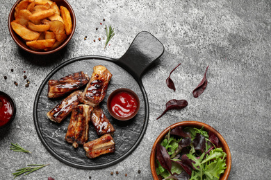 Photo of Delicious ribs on grey table, flat lay