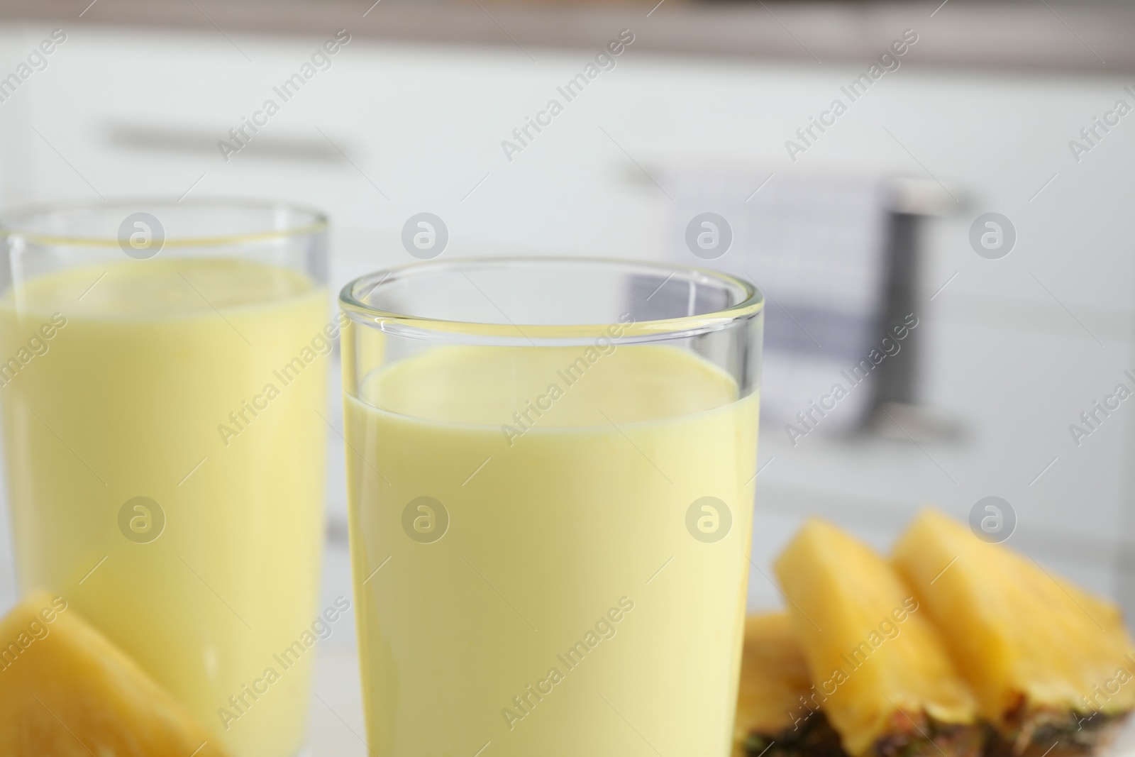 Photo of Glasses of tasty pineapple smoothie on blurred background, closeup