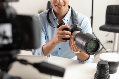 Photo of Male photo blogger recording video on camera indoors