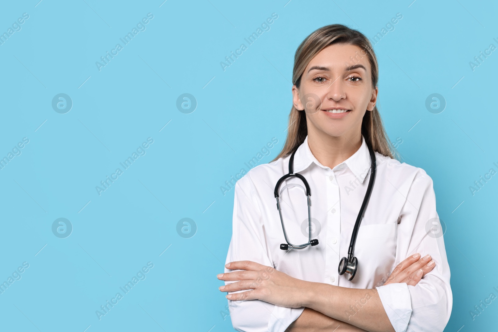 Photo of Portrait of happy doctor with stethoscope on light blue background, space for text
