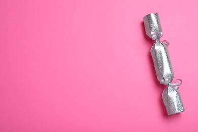 Photo of Silver Christmas cracker on pink background, top view. Space for text