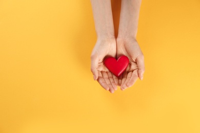 Woman holding decorative heart on color background, top view. Space for text