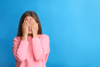 Young woman being blinded on blue background