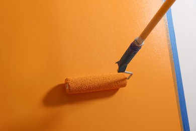 Photo of Painting wall with roller and orange dye