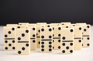 Photo of Domino tiles on wooden table against black background