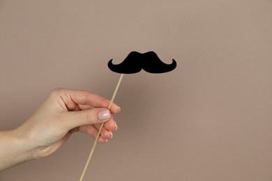 Photo of Woman with fake paper mustache on beige background, closeup. Space for text