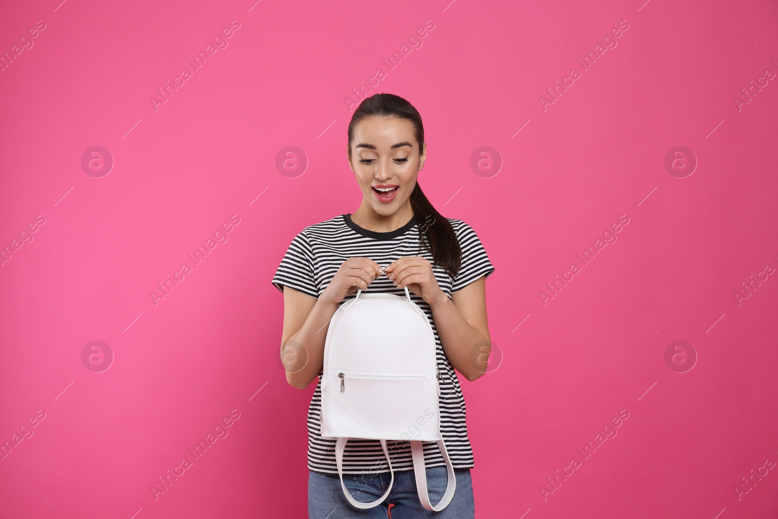 Photo of Excited young woman with stylish leather backpack on pink background
