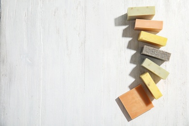 Hand made soap bars on white wooden background, top view. Space for text