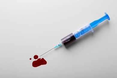 Photo of Plastic syringe with blood on white background, top view