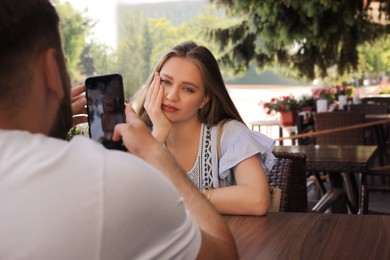 Photo of Young woman having boring date with guy in outdoor cafe