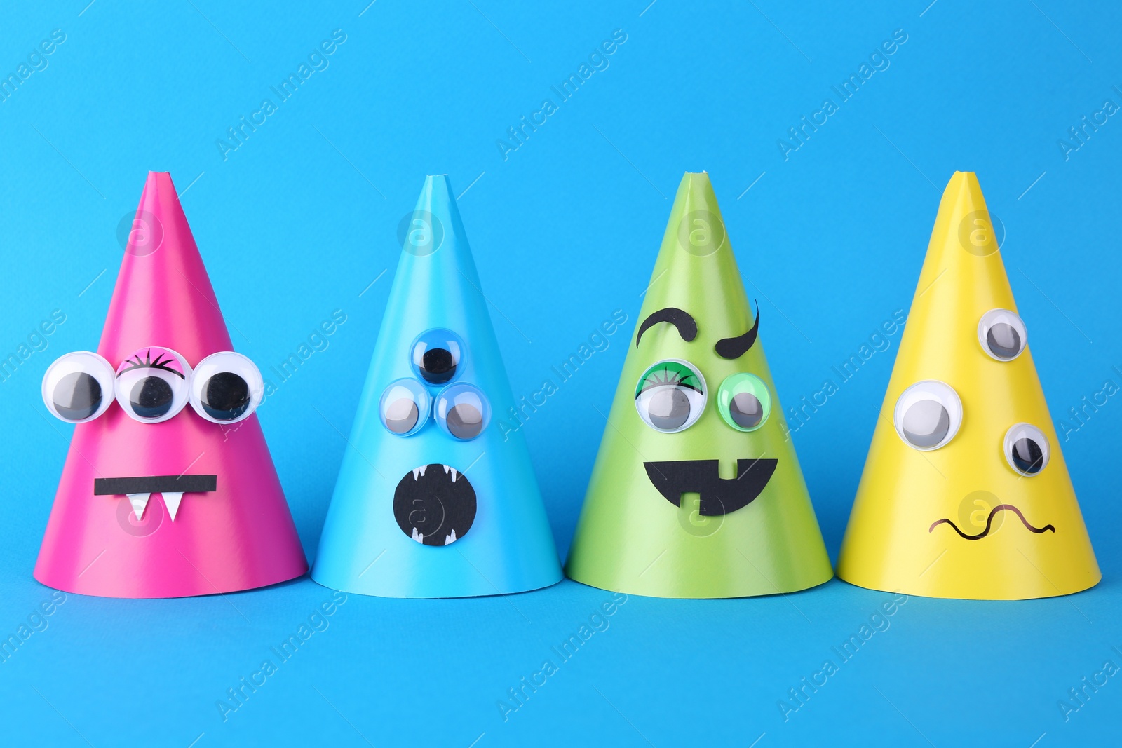 Photo of Spooky paper monsters on light blue background. Halloween decoration