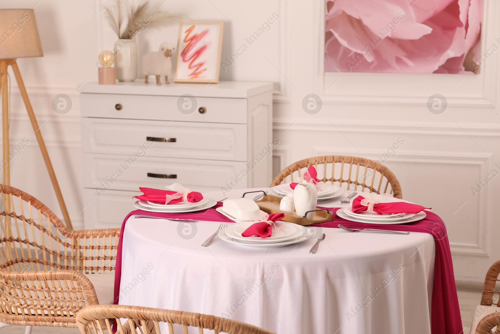 Photo of Color accent table setting. Plates, cutlery and pink napkins in dining room