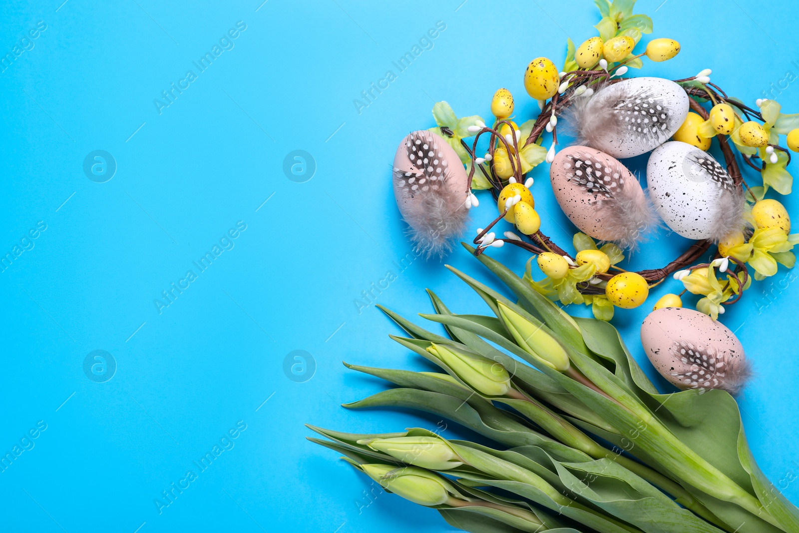 Photo of Flat lay composition with flowers and eggs on light blue background, space for text. Easter celebration