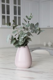 Photo of Vase with beautiful eucalyptus branches on white marble table in kitchen