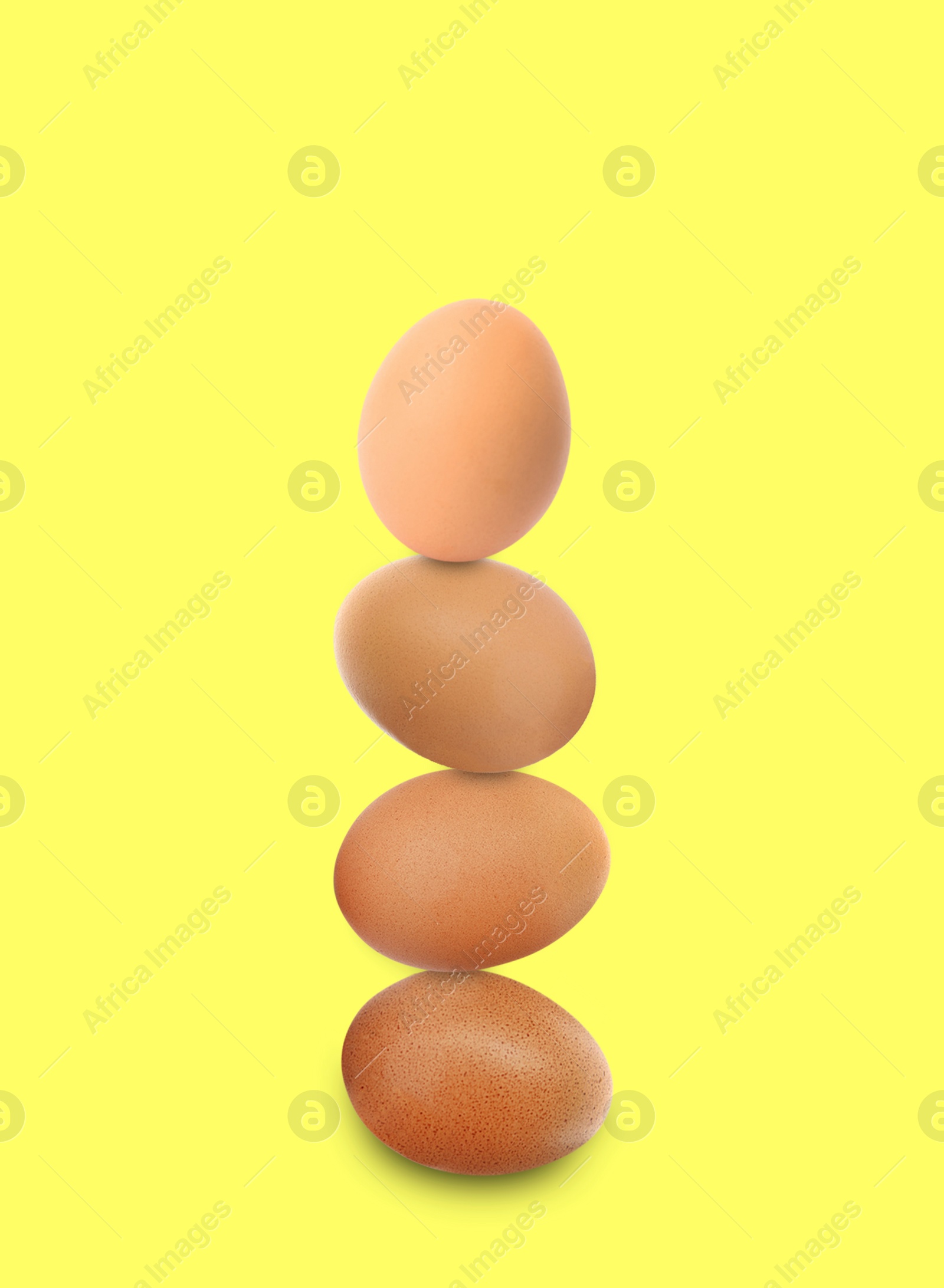 Image of Stacked fresh chicken eggs against light yellow background