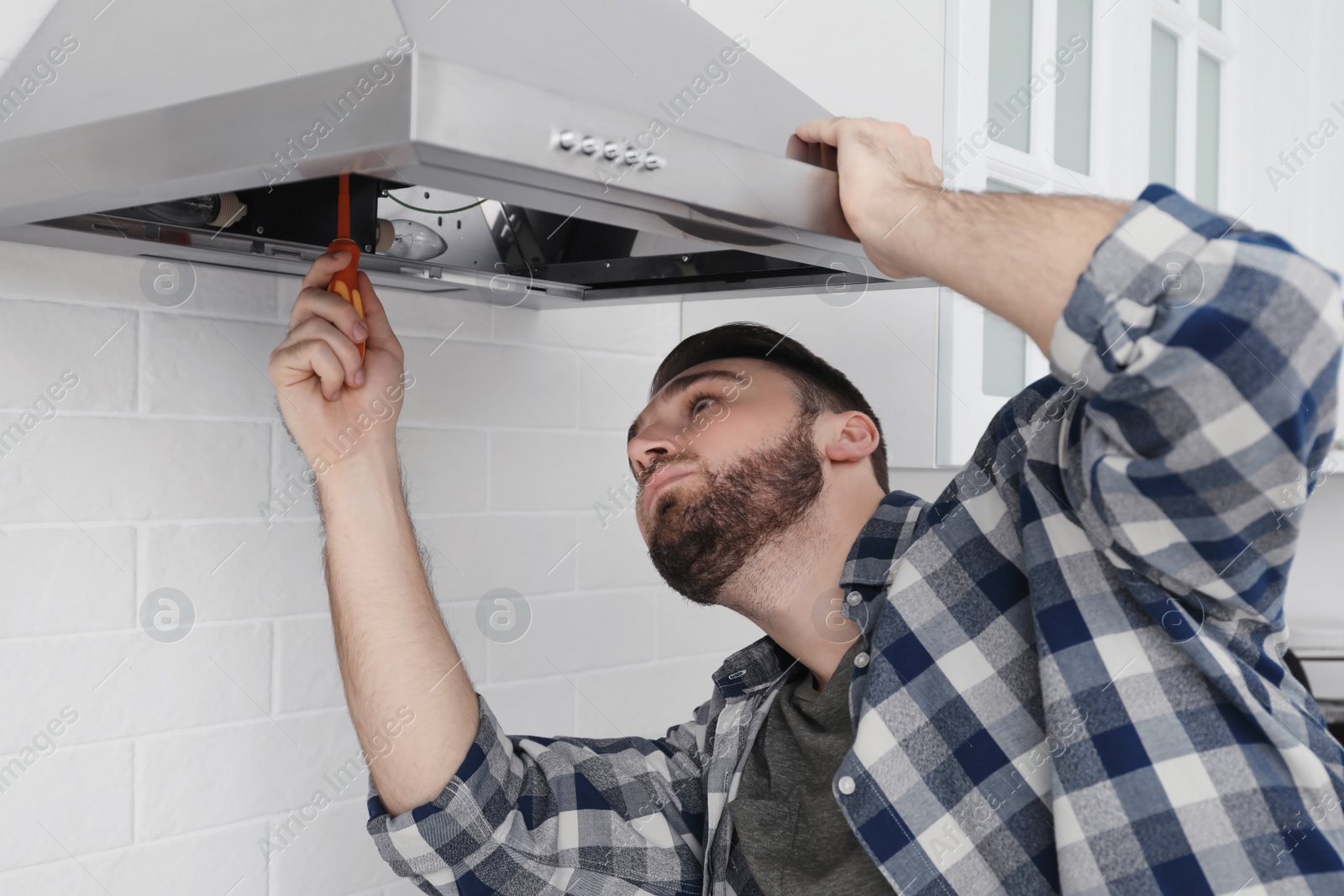 Photo of Man repairing modern cooker hood in kitchen