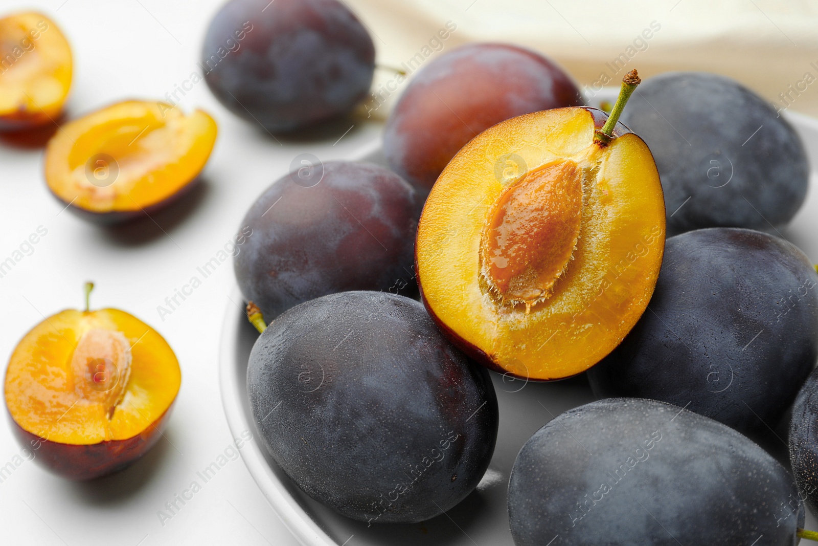 Photo of Tasty ripe plums on white table, closeup