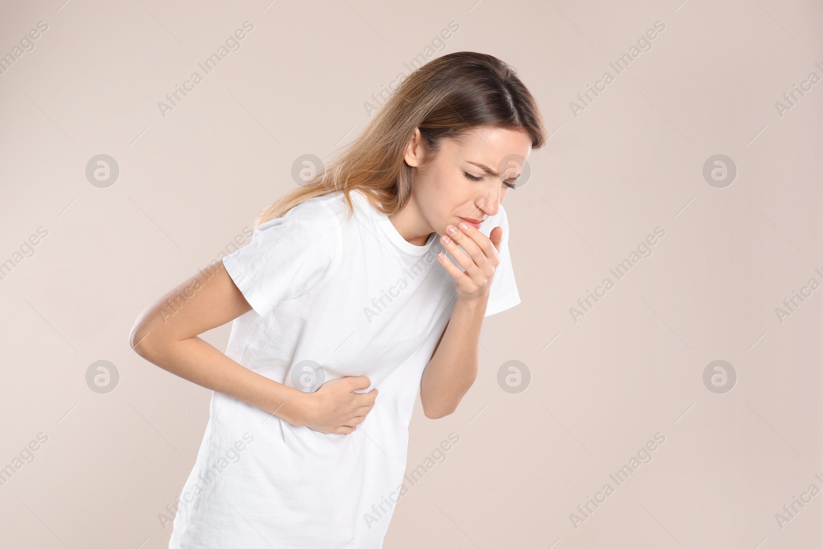 Photo of Woman suffering from nausea on beige background. Food poisoning