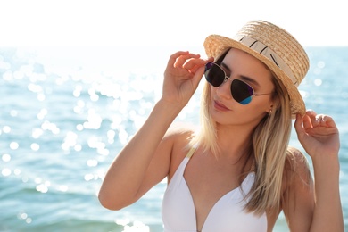 Photo of Beautiful woman wearing sunglasses near sea on sunny day