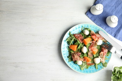 Photo of Flat lay composition of fresh melon with prosciutto on white wooden table. Space for text