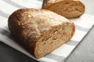 Photo of Cut loaf of bread on grey table, closeup