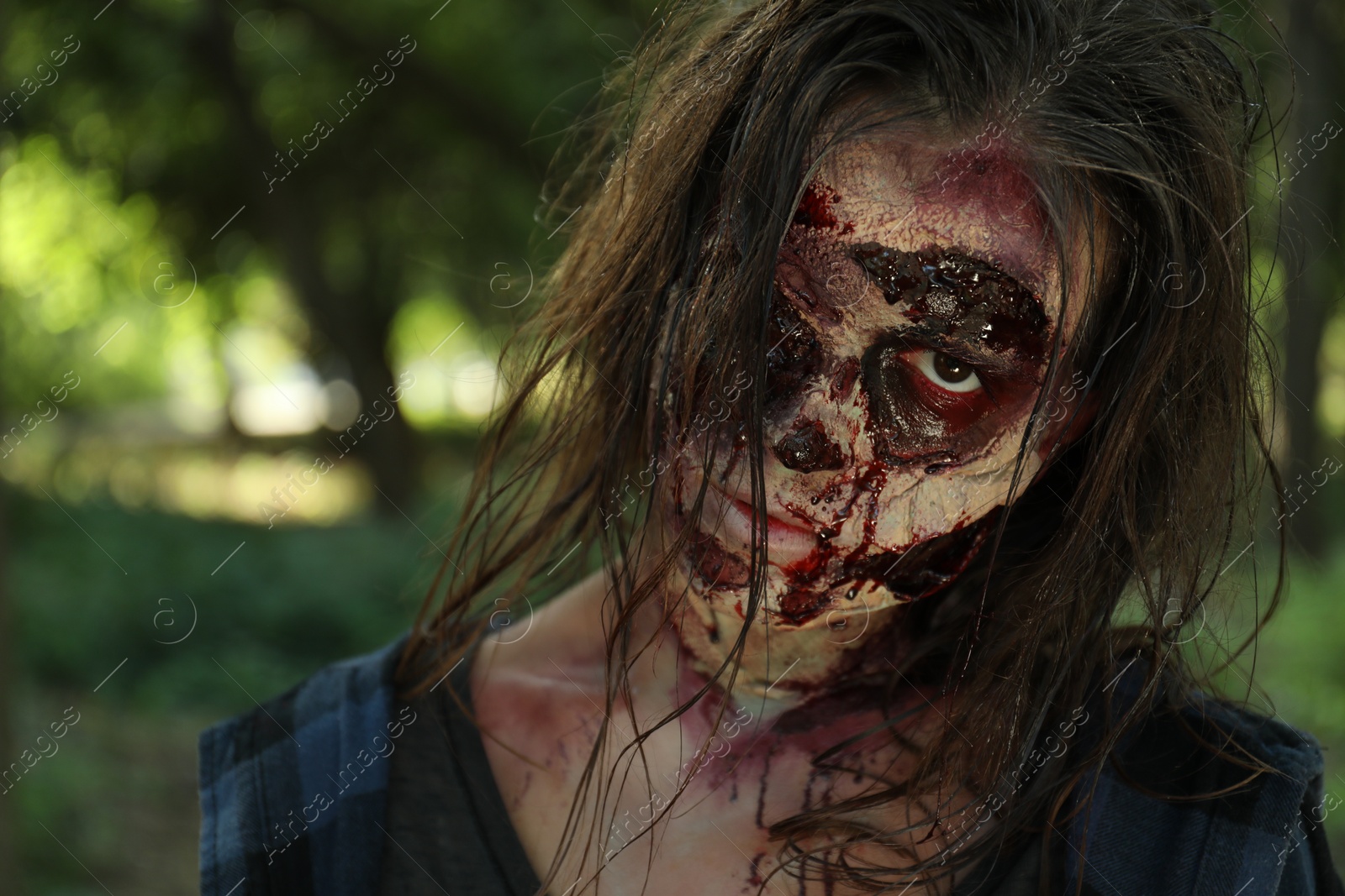 Photo of Scary zombie with bloody face outdoors, closeup. Halloween monster