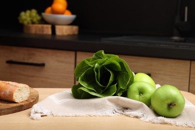 Photo of Ripe bok choy, green apples and baguette on table in kitchen