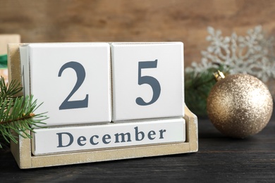 Photo of Block calendar and festive decor on black wooden table. Christmas countdown