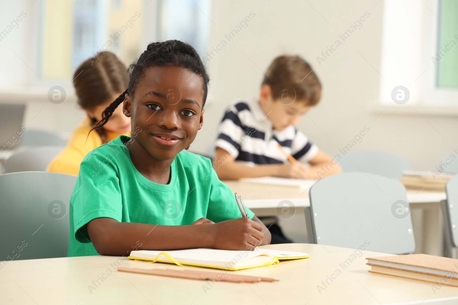 Photo of Portrait of smiling little boy studying in classroom at school. Space for text