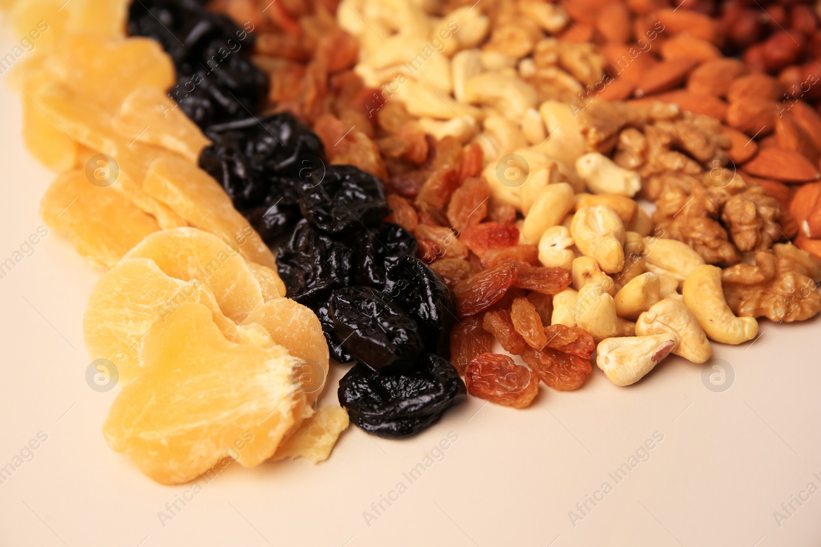 Photo of Mix of delicious dried nuts and fruits on beige background, closeup