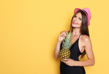 Sexy young woman in bikini with pineapple on color background