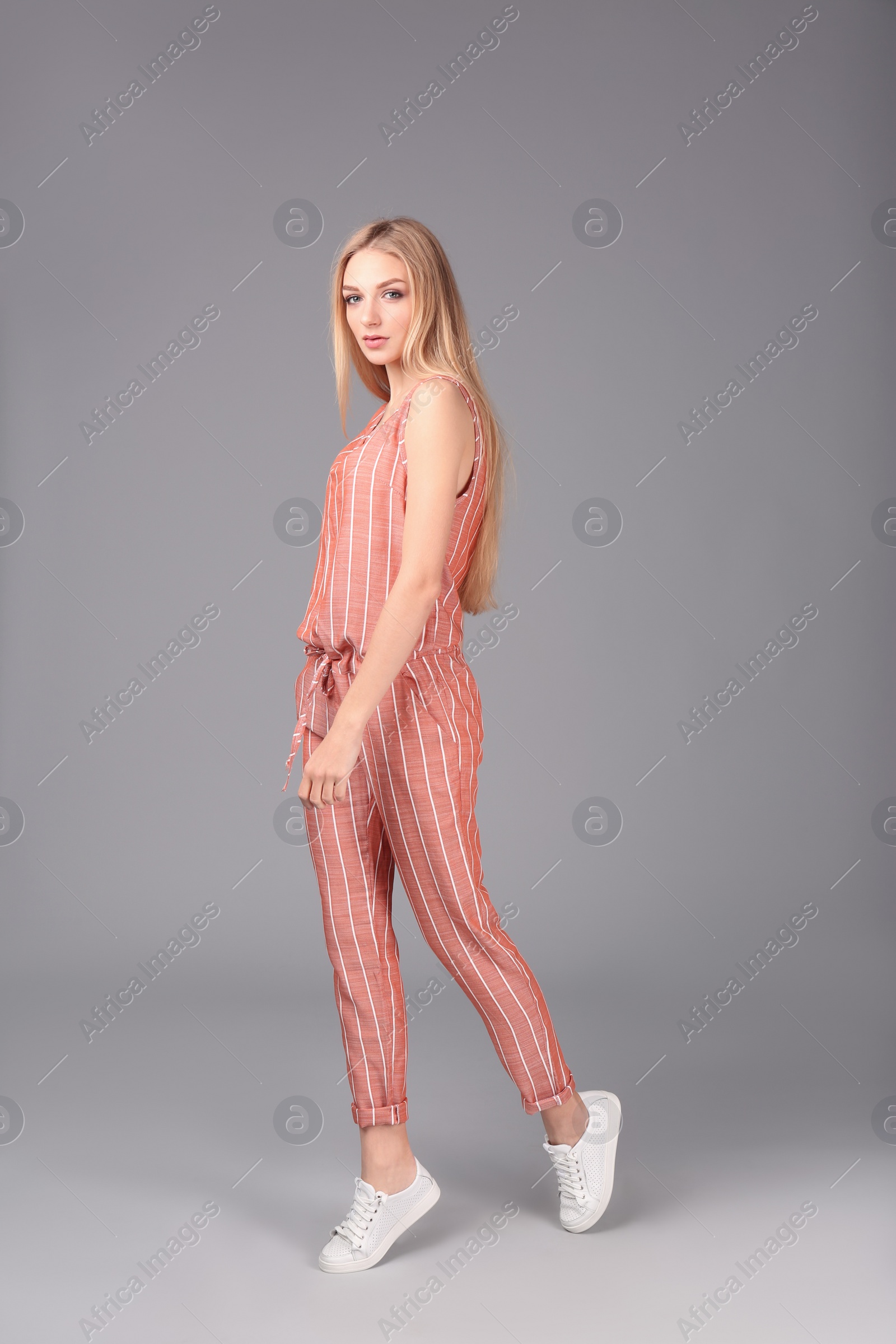 Photo of Young stylish woman in trendy sport shoes on grey background