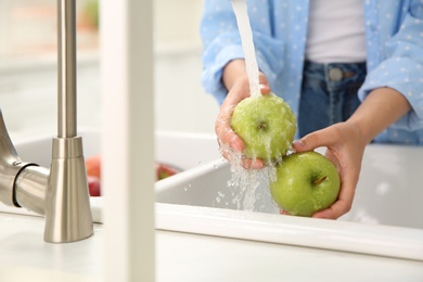 Photo of Woman washing fresh green apples in kitchen sink, closeup