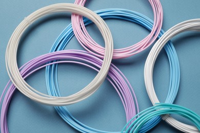 Photo of Colorful plastic filaments for 3D pen on light blue background, flat lay
