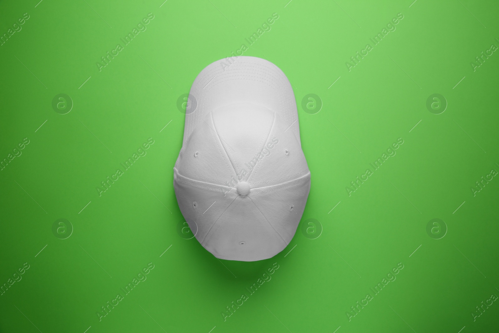 Photo of Stylish white baseball cap on light green background, top view