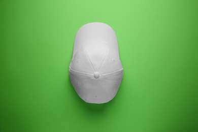 Photo of Stylish white baseball cap on light green background, top view