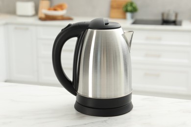 Modern electric kettle on table in kitchen