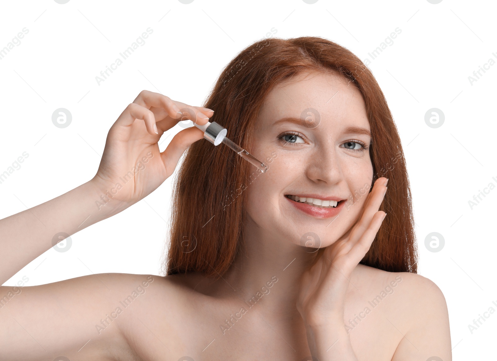 Photo of Smiling woman with freckles applying cosmetic serum onto her face against white background