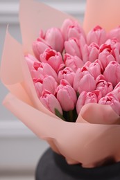 Photo of Bouquet of beautiful pink tulips in vase near white wall, closeup