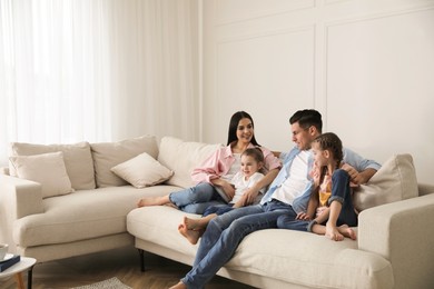 Photo of Happy family resting on comfortable sofa in living room