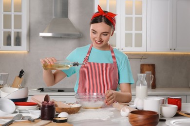 Photo of Smiling woman cooking in kitchen. Dirty dishware and utensils on messy countertop