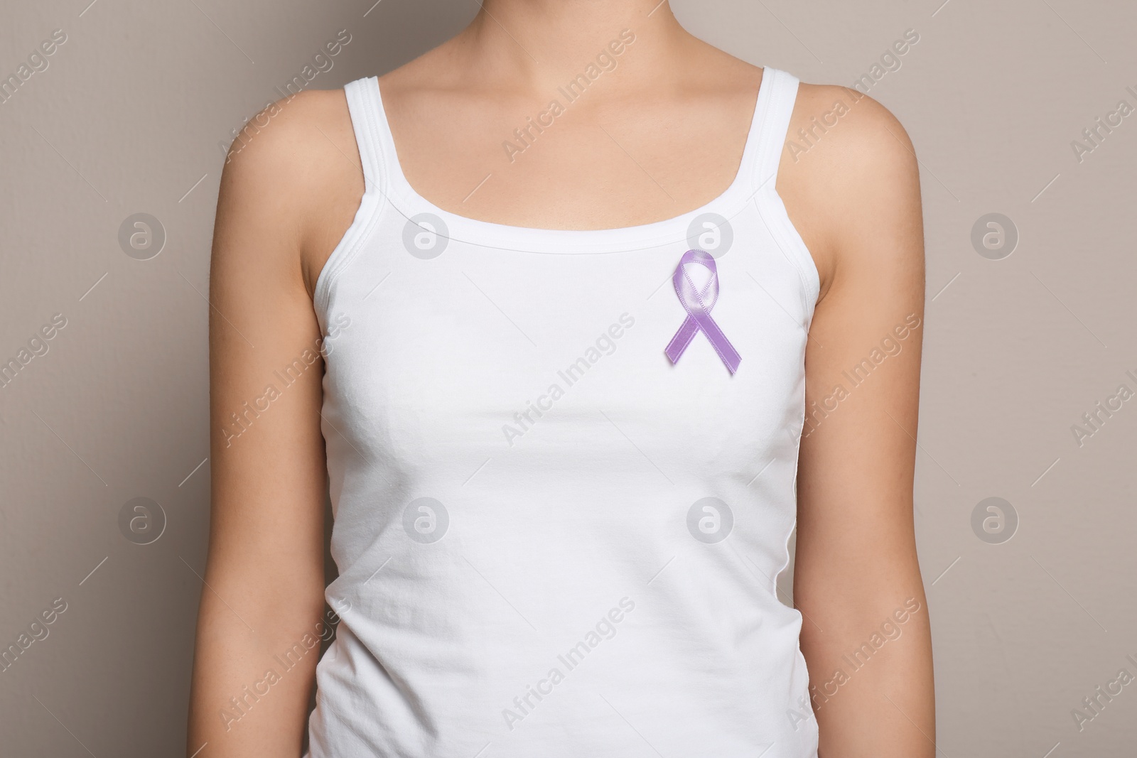 Photo of Woman wearing purple ribbon on grey background, closeup. Domestic violence awareness