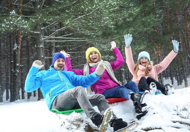 Photo of Happy family sledding in forest on snow day